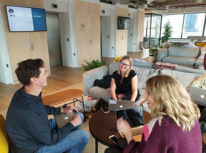 Three people sit around working together in an office