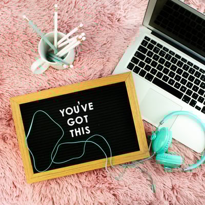 laptop, headphones and pencils with positive affirmation on a blackboard