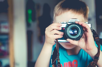 small boy takes photograph with camera